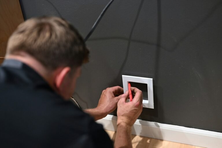 Electrician fitting a white wall switch plate